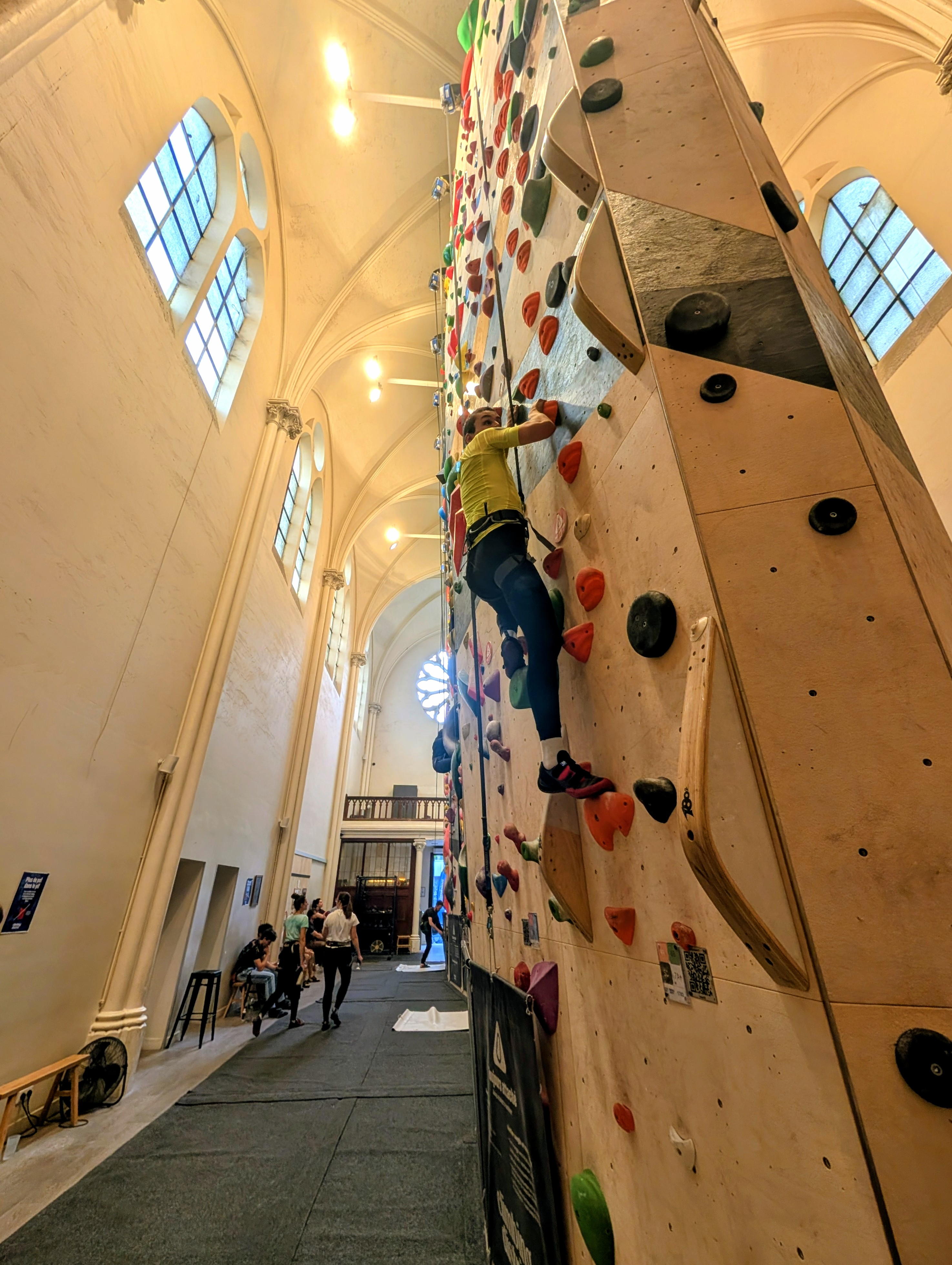 Un duo A2CMieux à l'escalade, guide et sportif déficient visuel progressant ensemble sur un mur.