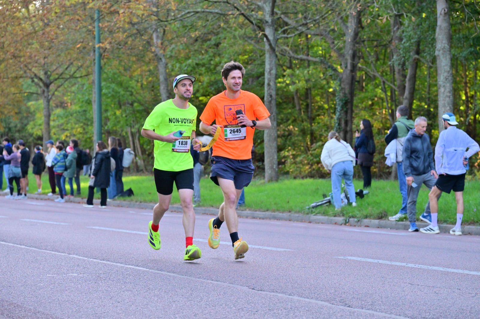 Alexandre, coureur non-voyant, et son guide Thibaut reliés par un cordon au semi-marathon du Bois de Vincennes.