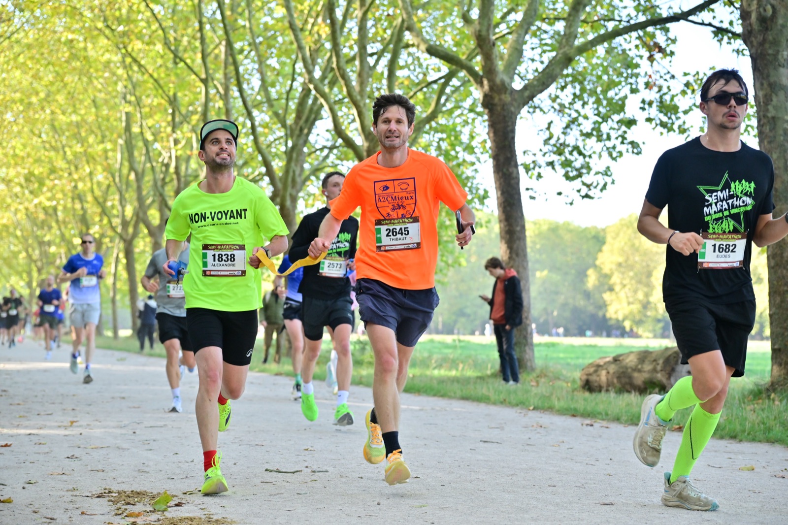 Alexandre, tout sourire, guidé par Thibaut en maillot A2CMieux sur une allée du Bois de Vincennes.
